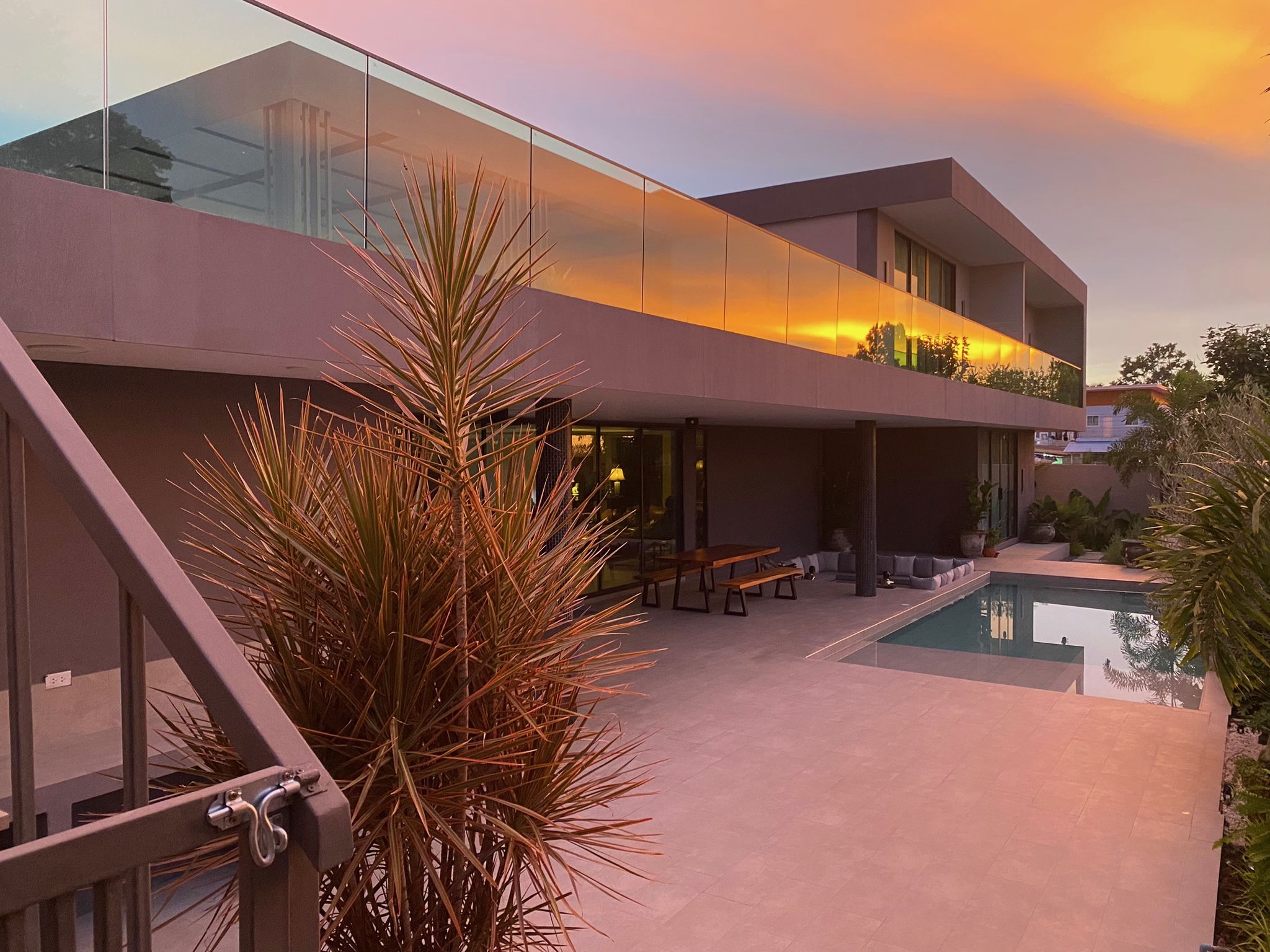 Villa Koh exterior at golden sunset, with pool and tropical garden