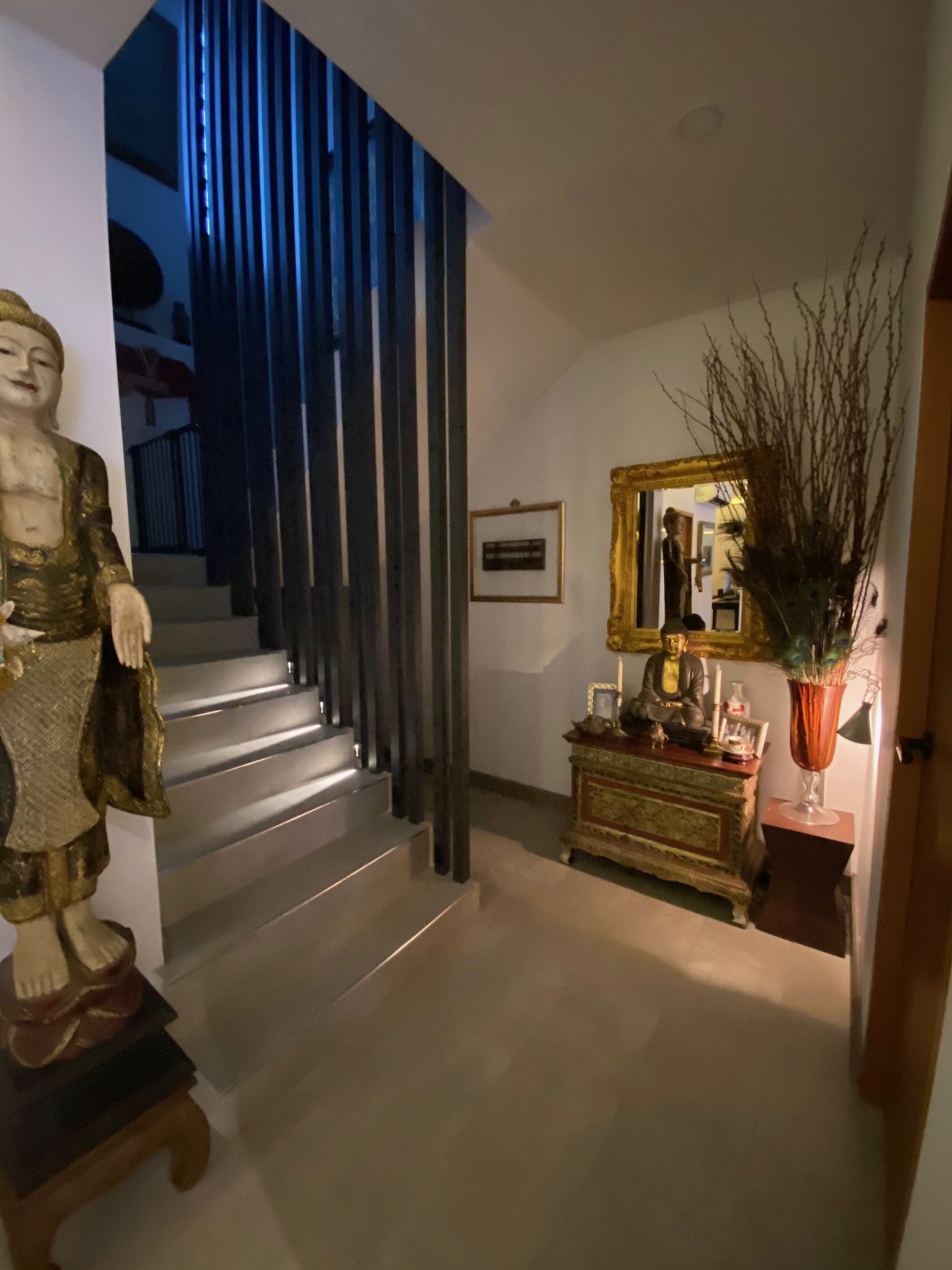 Statement staircase with vertical steel fins and antique Buddha at night